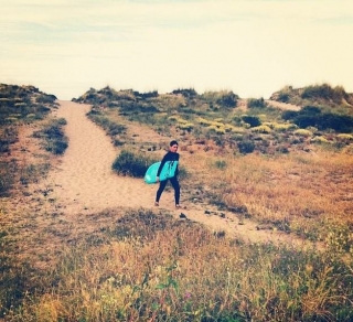 nino con una tabla de surf caminando por una playa
